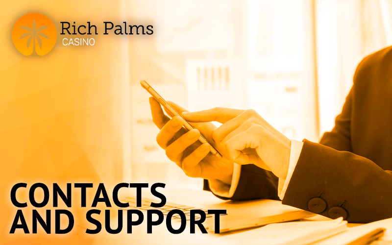 A man in a suit holding a phone in his hand and the Rich Palms logo